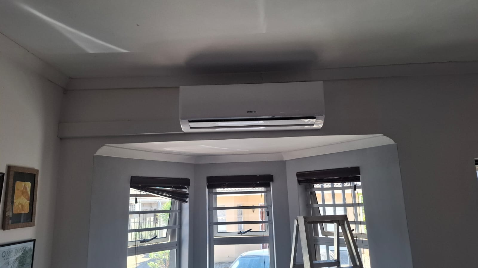 Samsung indoor unit mounted on the wall above a bay window