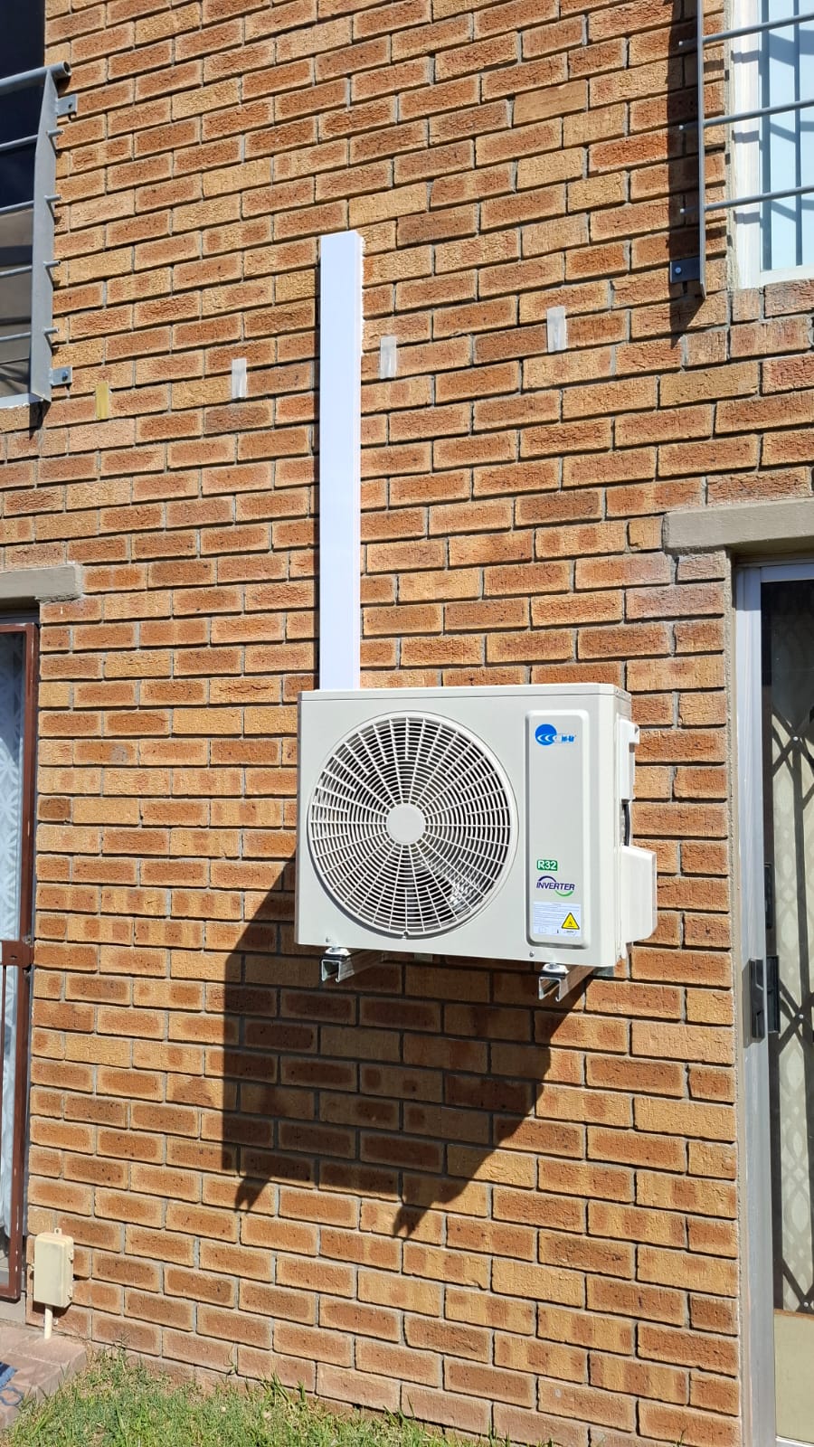 Jet-Air R32 inverter outdoor unit on a face-brick wall with white trunking running up to the indoor unit