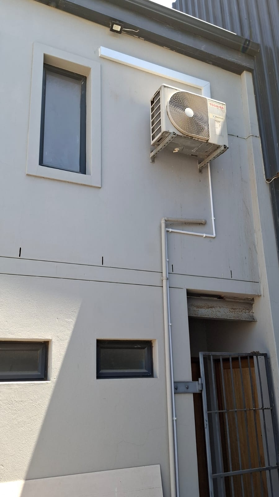 Outdoor unit on a wall bracket with the condensate pipe running down to ground level