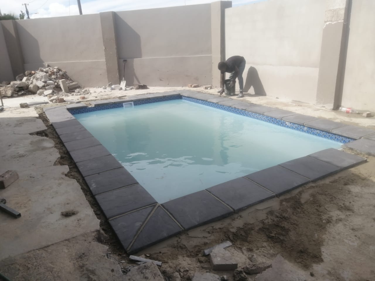 Completed fibreglass pool filled with water and finished with dark grey coping
